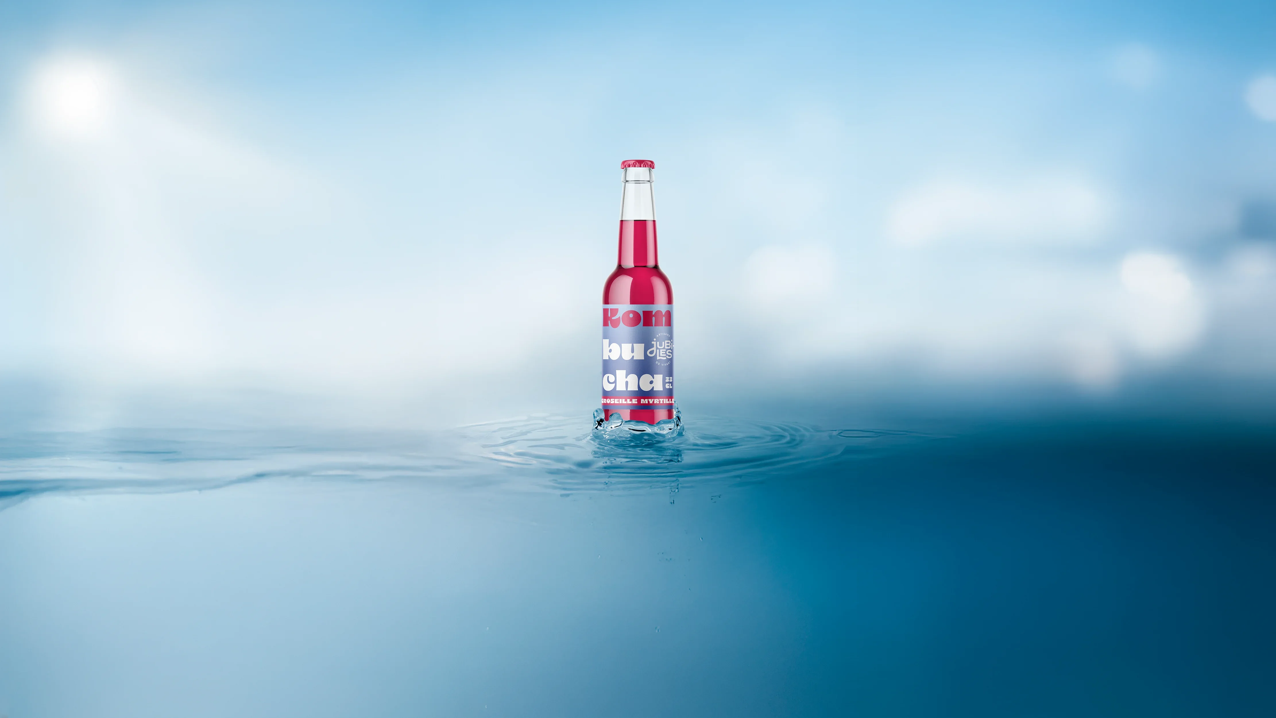 Photographie d'une bouteille de Kombucha rouge sur un fond bleu dégradé, création d'identité graphique.