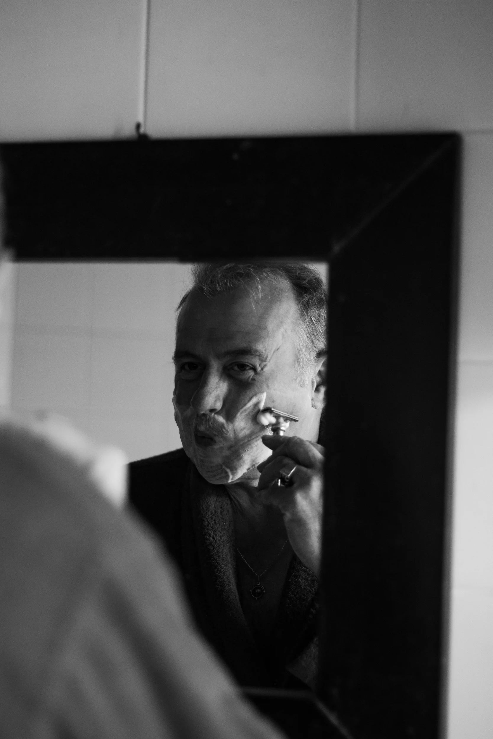 Yves Groise rasoir à la main devant son miroir